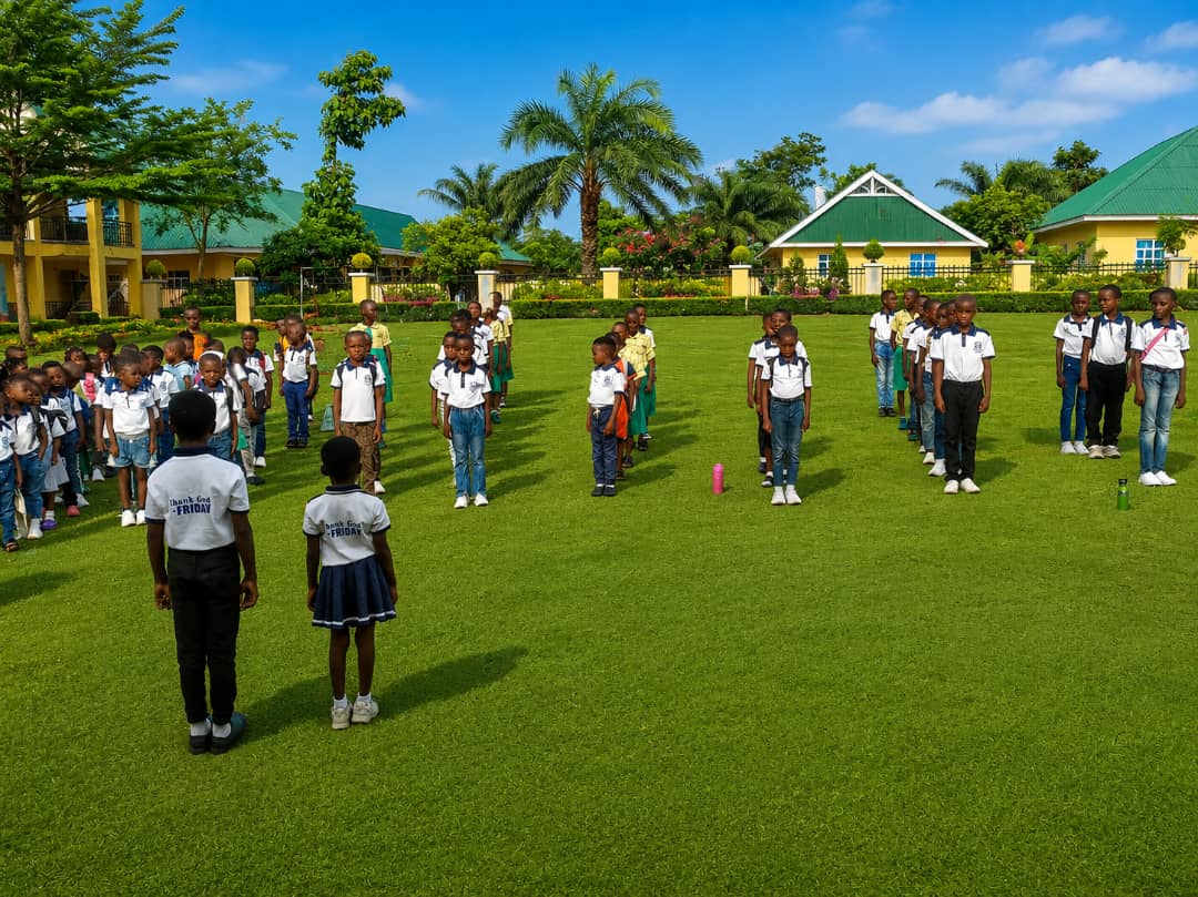 Onimag Academy pupils assembled on the school field with the landscaped campus buildings behind them